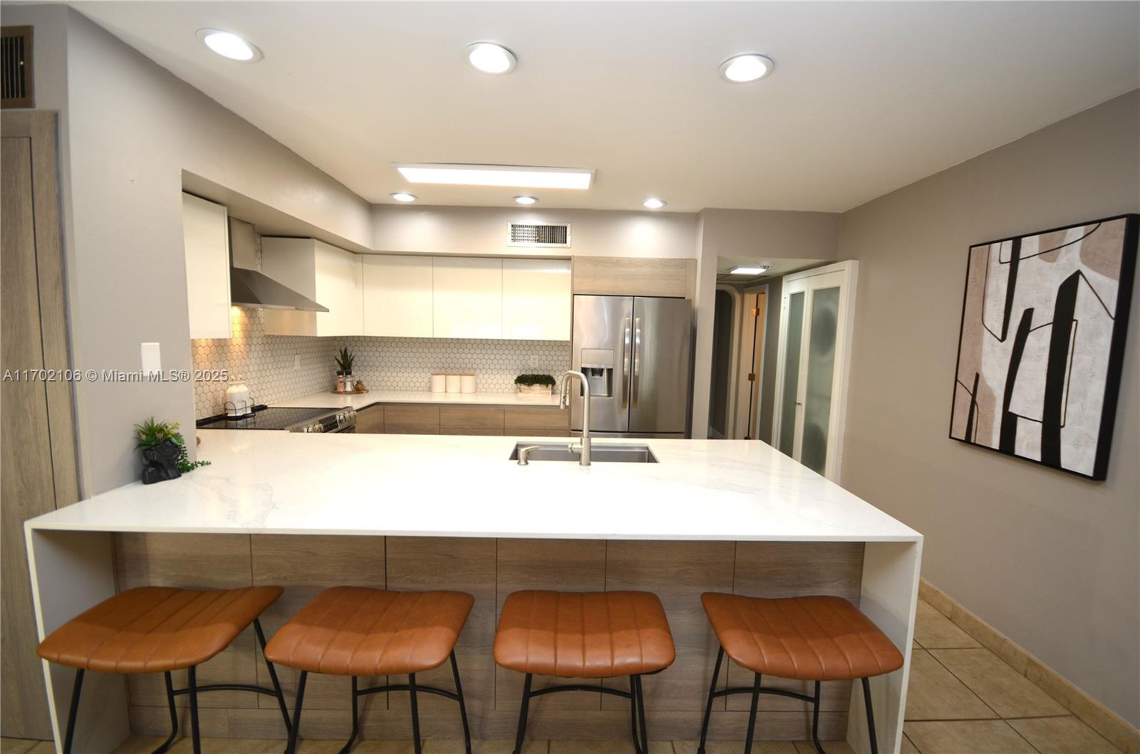 a kitchen with stainless steel appliances granite countertop a kitchen island and chairs in it