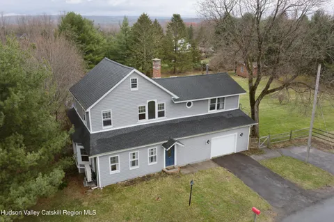 a aerial view of a house with yard and trees in the background