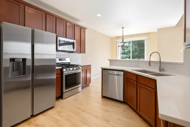 a kitchen with stainless steel appliances granite countertop a sink a stove and a refrigerator