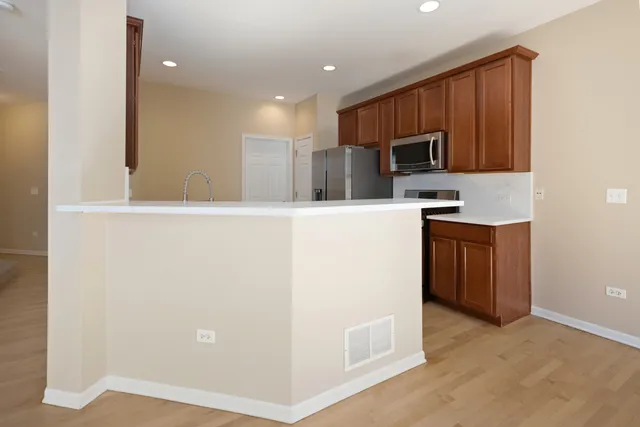 a kitchen with stainless steel appliances kitchen island granite countertop a stove a sink and a refrigerator with wooden floor