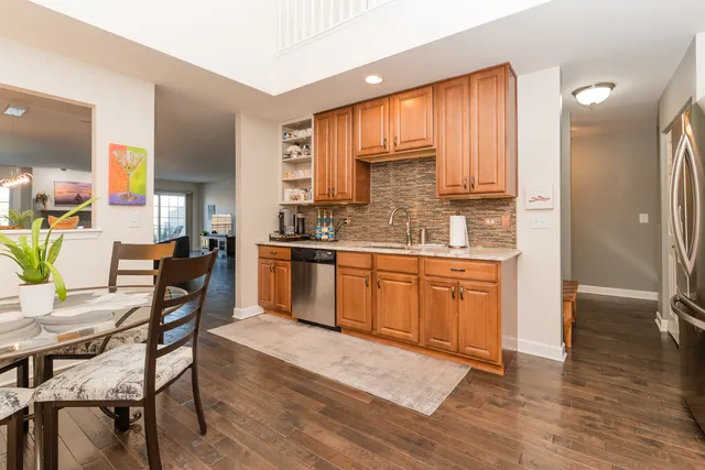 a kitchen with stainless steel appliances granite countertop wooden cabinets a stove a sink a kitchen island with chairs and wooden floor