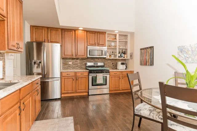 a kitchen with stainless steel appliances granite countertop a refrigerator and wooden cabinets