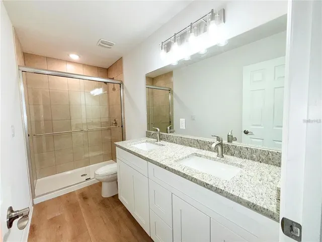 a bathroom with a granite countertop sink toilet and shower