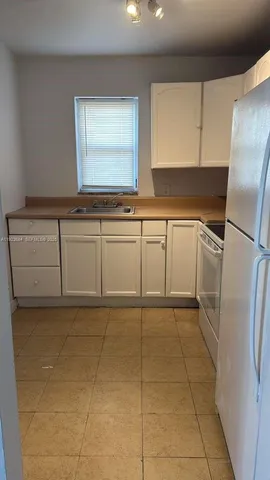 a kitchen with white cabinets a refrigerator and a sink