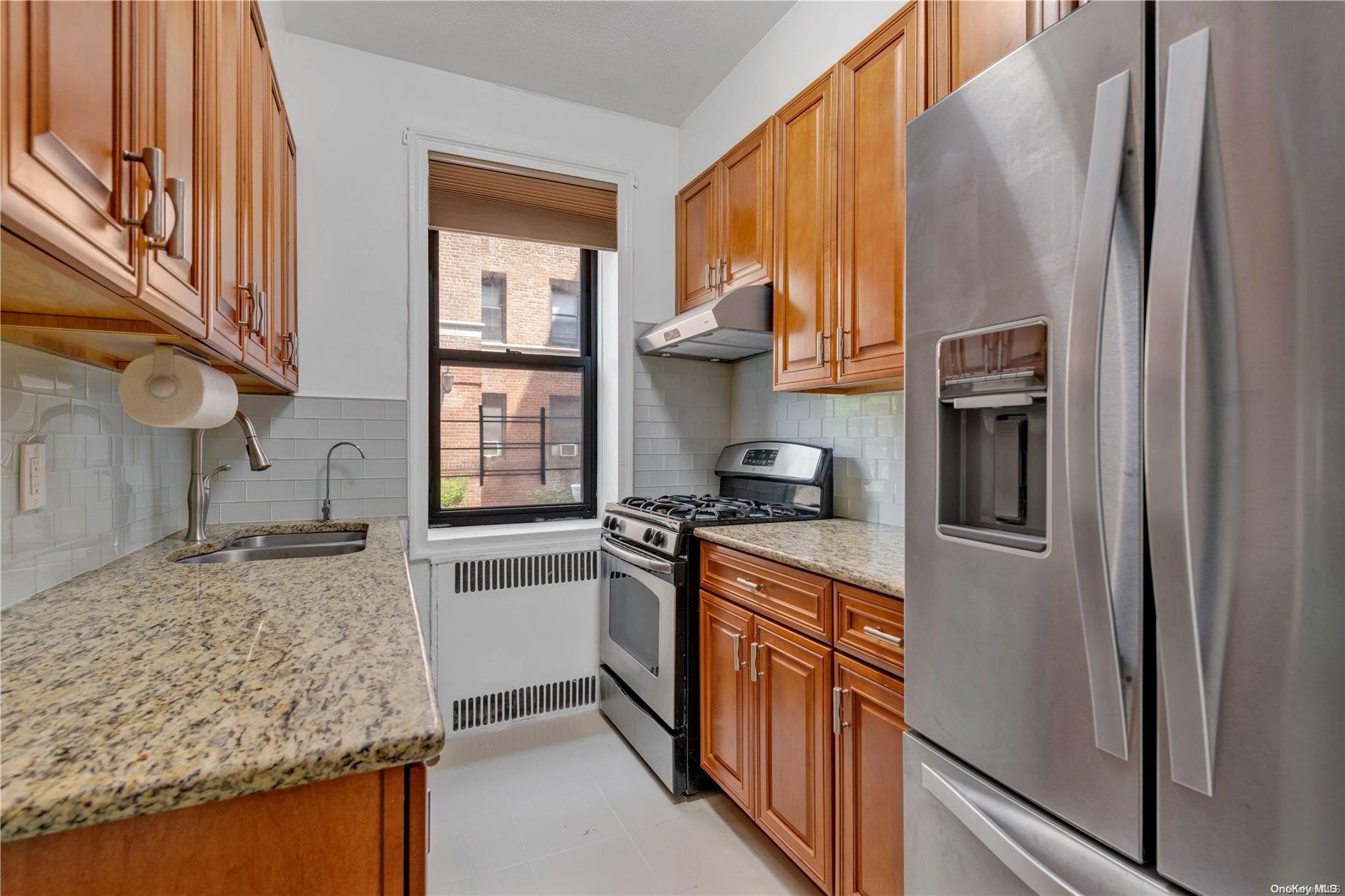 21 Barstow Road, Unit 1G Great Neck, NY 11021 - Photo 1 of 1 a kitchen with stainless steel appliances granite countertop a refrigerator a stove and a sink with wooden floor