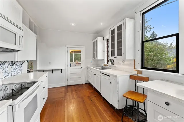 a large white kitchen with sink and wooden floor