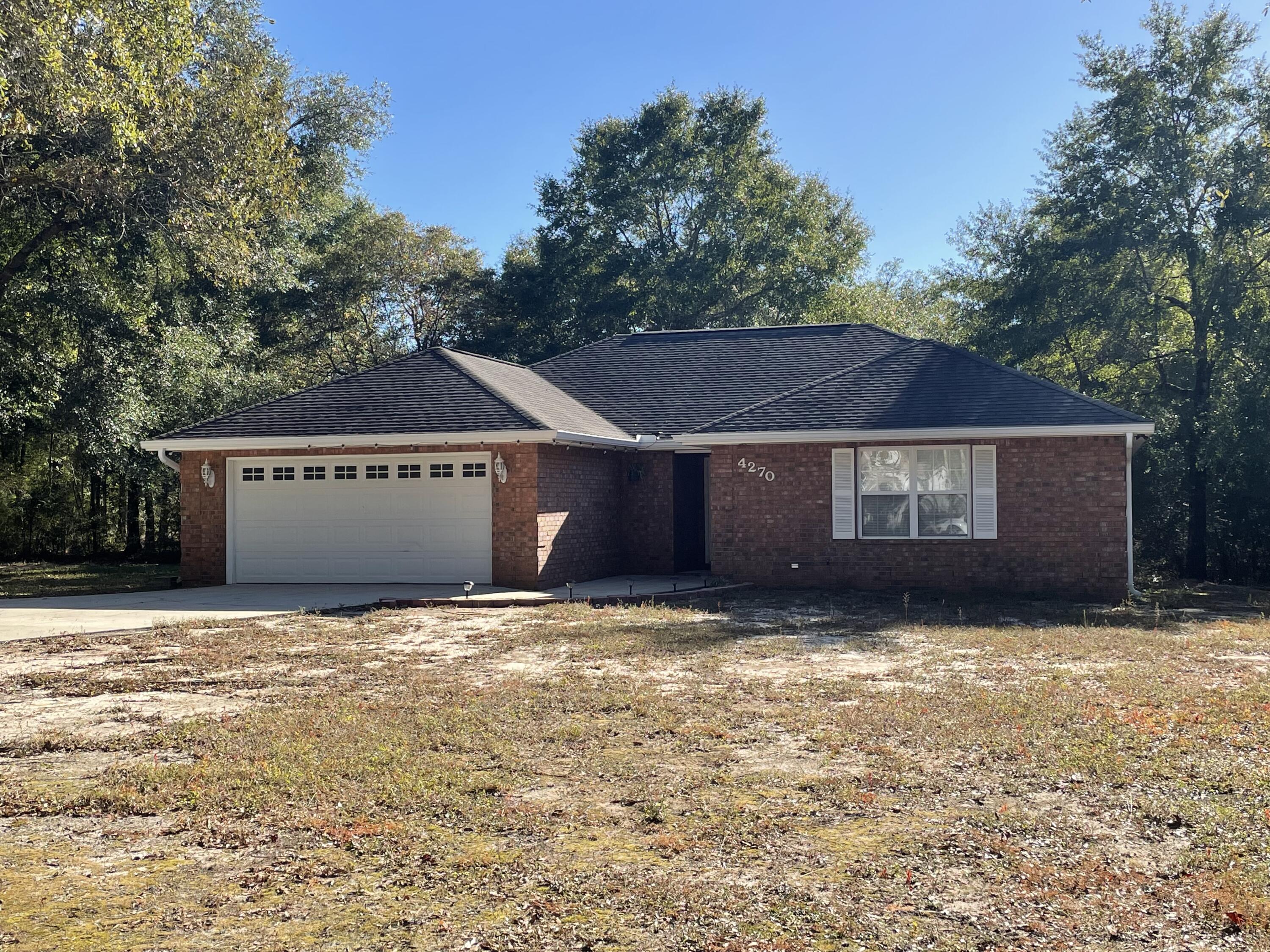 a view of house with yard and trees in the background