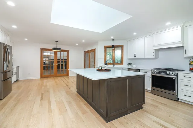 a kitchen with stainless steel appliances granite countertop a stove a sink dishwasher and a refrigerator with wooden floor