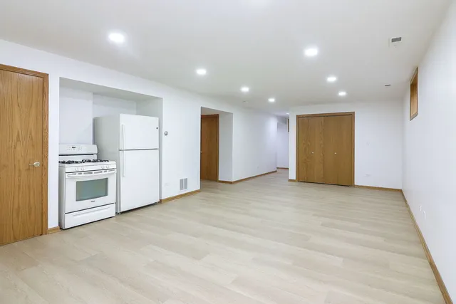 a view of empty room with kitchen appliances and wooden floor