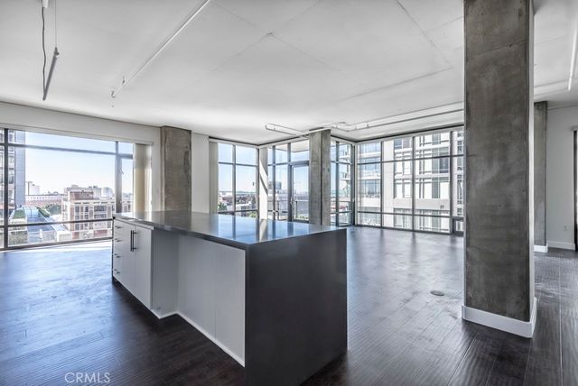 a living room with stainless steel appliances wooden floor and a large window
