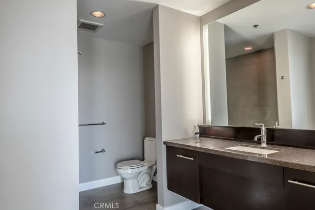 a bathroom with a granite countertop sink toilet and mirror