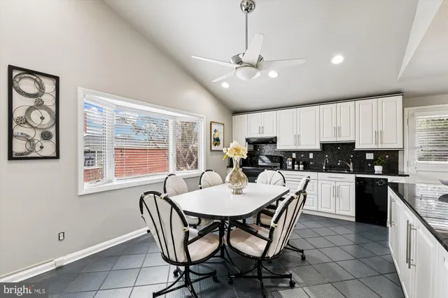 a kitchen with stainless steel appliances granite countertop a stove top oven a sink a dining table and chairs