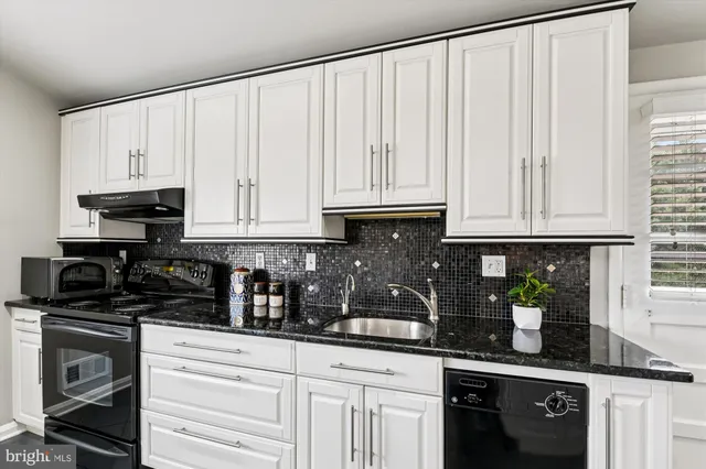 a kitchen with white cabinets and black appliances