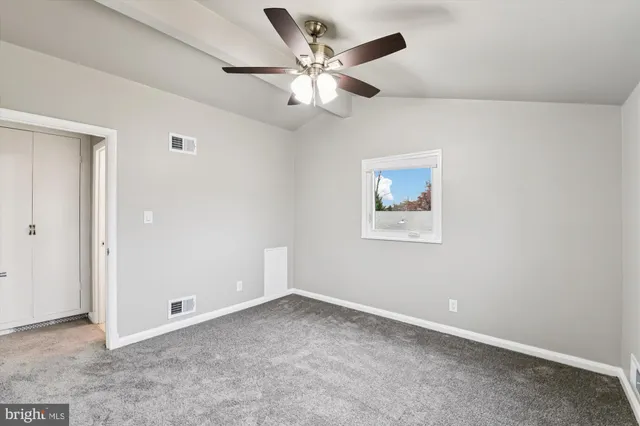 an empty room with ceiling fan and window