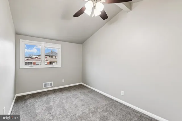 an empty room with a window and a fan