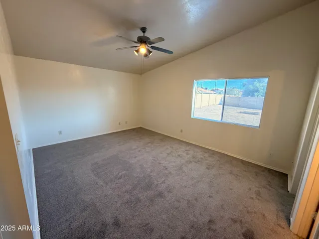 en empty room with windows and chandelier fan