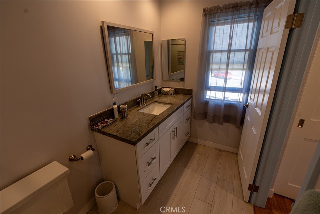258 West Escalones, Unit 6R San Clemente, CA 92672 - Photo 21 of 22 a bathroom with a granite countertop sink a mirror and a toilet