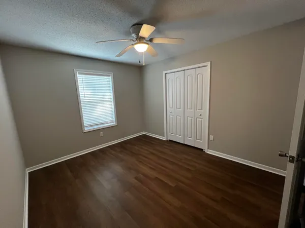 an empty room with wooden floor and windows
