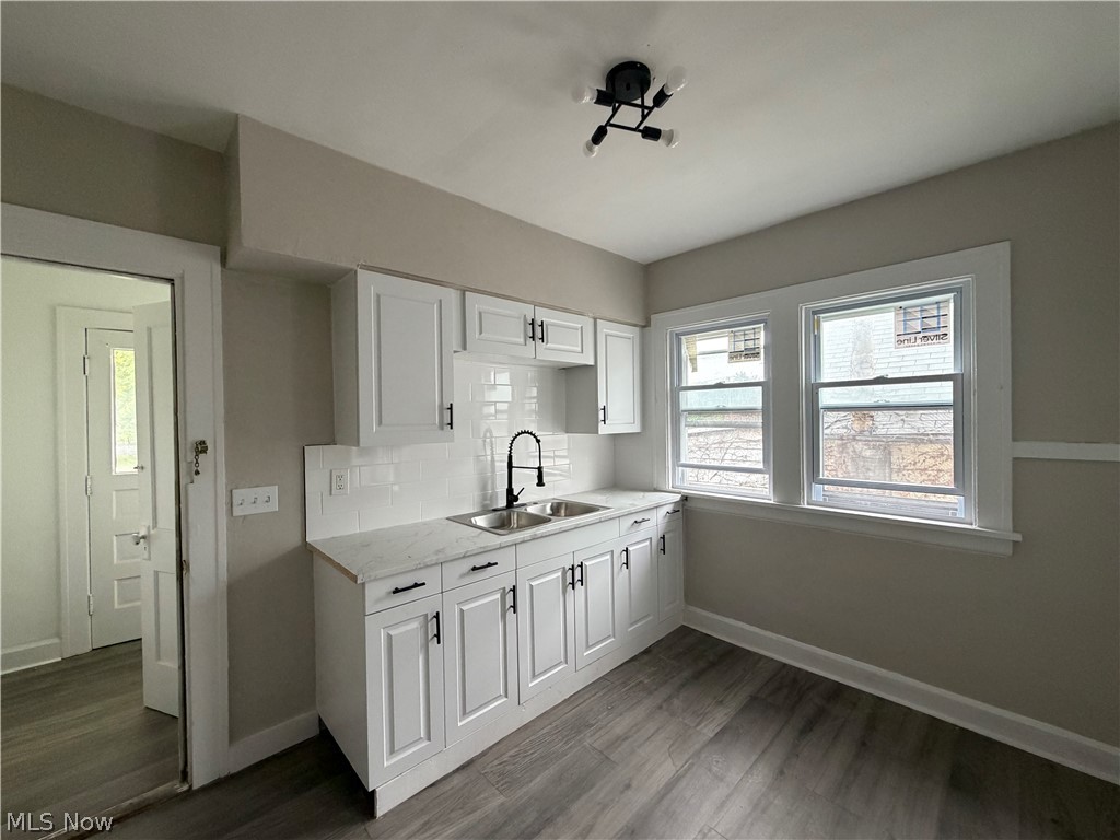 15317 Shiloh Road Cleveland, OH 44110 - Photo 15 of 29 Kitchen featuring white shaker-style cabinetry with matte black hardware, a double basin stainless steel sink with a matte black faucet, and a subway tile backsplash
