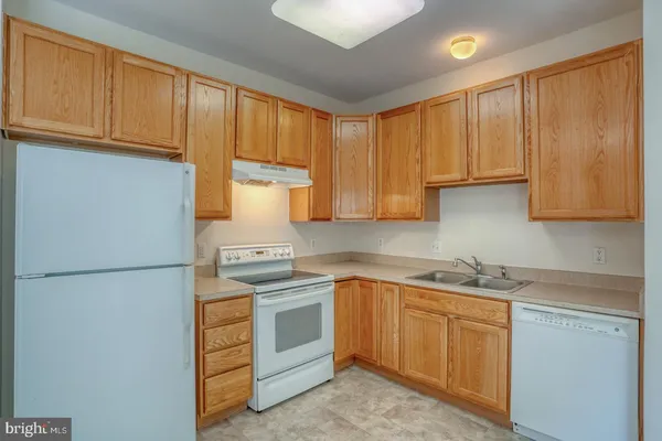 a kitchen with stainless steel appliances granite countertop a refrigerator a stove a sink and dishwasher with a dining table