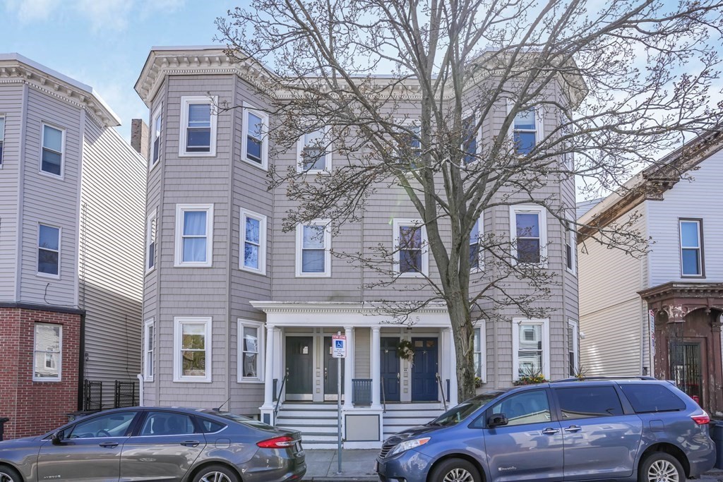 a front view of a building with parking space and a car park in front of it