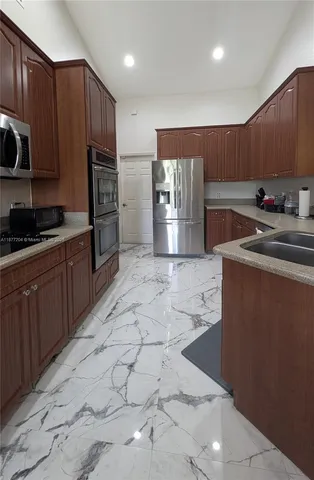 a kitchen with stainless steel appliances a sink a stove a refrigerator cabinets and a counter top space