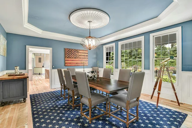a dining room with wooden floor a chandelier a glass table and chairs