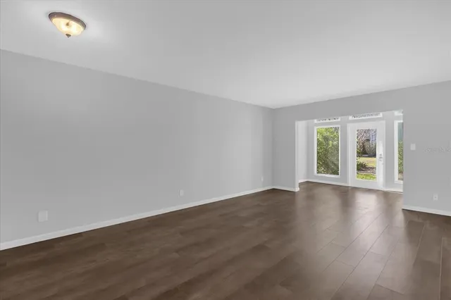 a view of an empty room with wooden floor and window