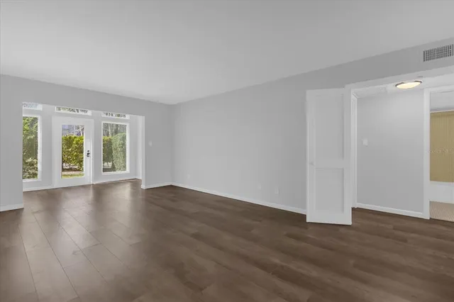 a view of an empty room with wooden floor and a window