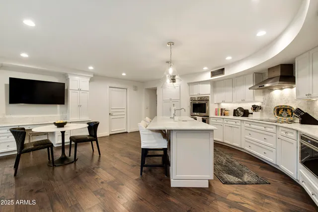 a kitchen with stainless steel appliances a dining table chairs microwave and sink
