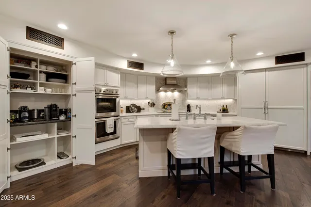 a kitchen with stainless steel appliances granite countertop a table chairs stove and white cabinets