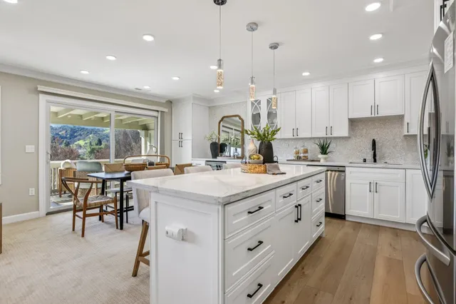 a kitchen with kitchen island granite countertop a stove a sink a dining table and chairs with wooden floor