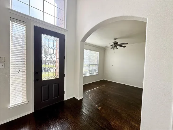 an empty room with wooden floor cabinet and windows