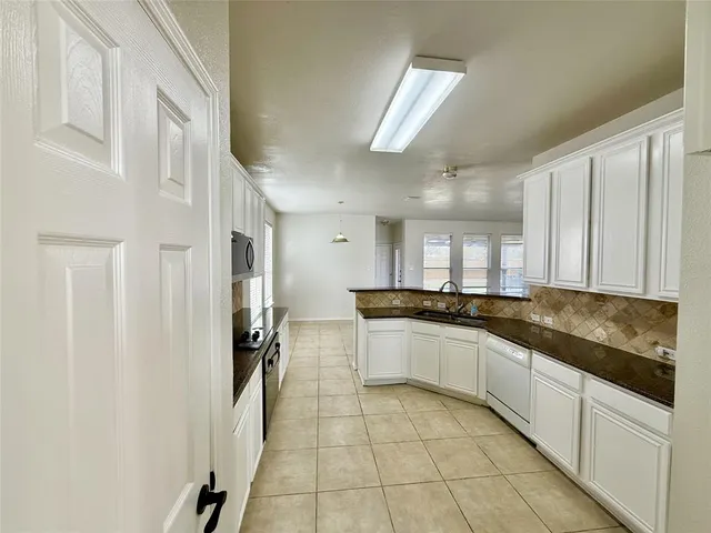 a large white kitchen with granite countertop a sink
