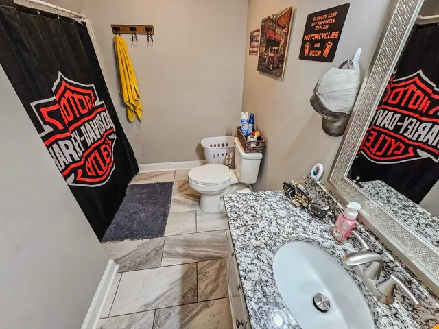 a bathroom with a granite countertop sink a toilet and a mirror