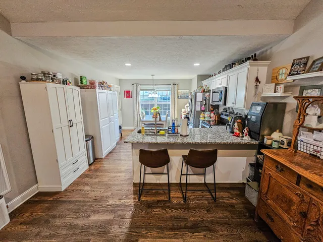 a kitchen with stainless steel appliances granite countertop a stove top oven a sink dishwasher and cabinets with wooden floor