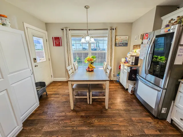 a kitchen with stainless steel appliances granite countertop a stove top oven a dining table and chairs with wooden floor