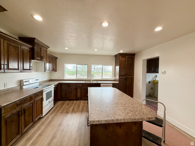 2865 North 3250 W Road Sutherland, UT 84624 - Photo 5 of 28 Spacious kitchen featuring wood-finish flooring, recessed lighting, ample dark wood cabinetry with matte black hardware, and an expansive island with a speckled countertop