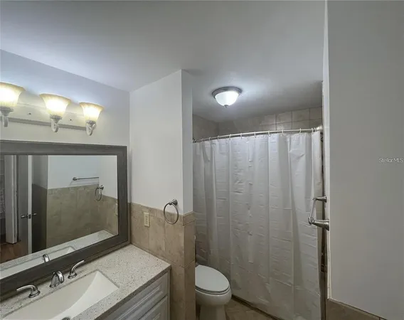 a bathroom with a granite countertop sink toilet a mirror and shower