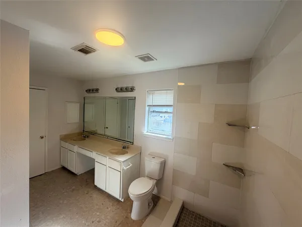 a bathroom with a granite countertop toilet a sink and mirror