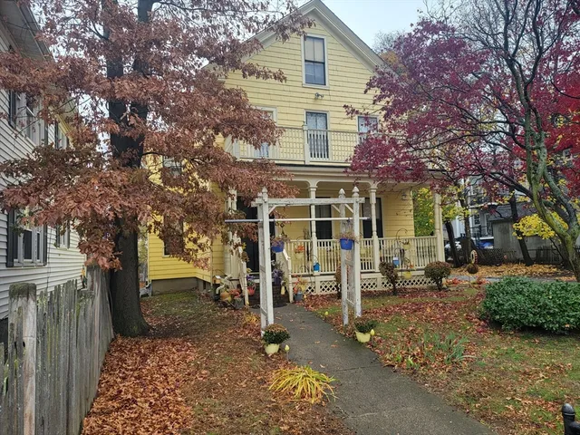 a view of a house with a yard and large trees
