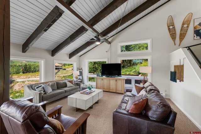 a living room with furniture a flat screen tv and a large window