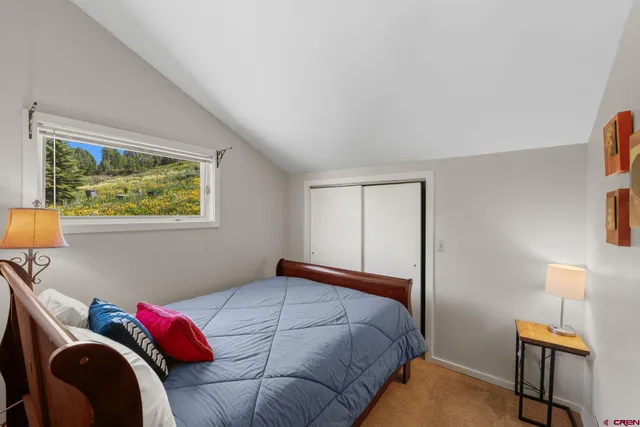 a bedroom with a bed and a lamp on dresser