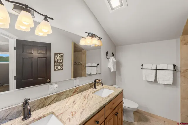 a bathroom with a granite countertop sink a toilet and mirror