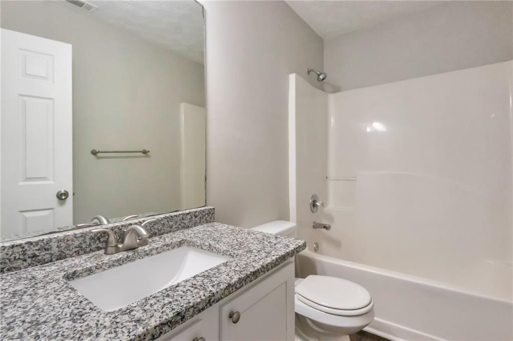 344 Springbottom Court Southeast Lawrenceville, GA 30046 - Photo 18 of 26 a bathroom with a granite countertop sink a toilet and shower
