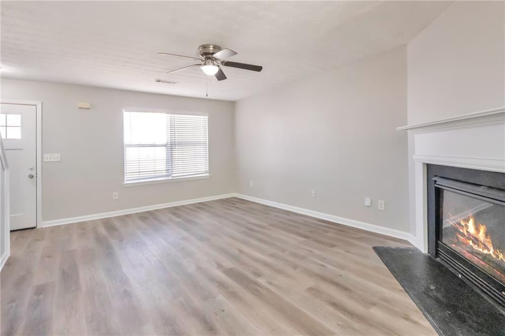 344 Springbottom Court Southeast Lawrenceville, GA 30046 - Photo 5 of 26 an empty room with wooden floor fireplace and windows