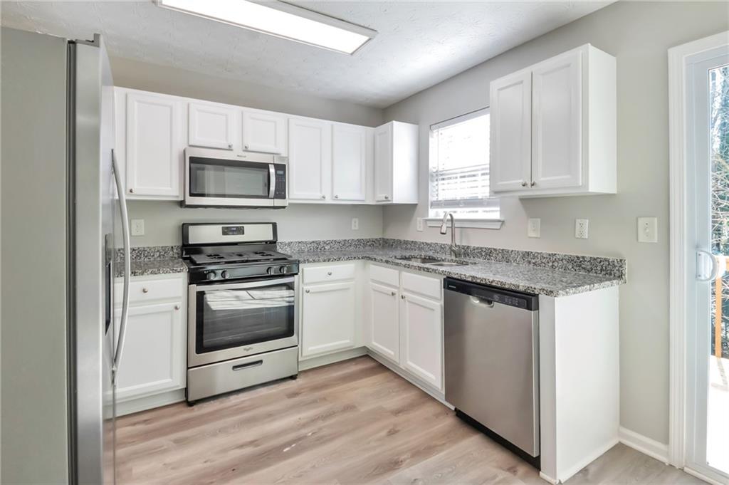 344 Springbottom Court Southeast Lawrenceville, GA 30046 - Photo 6 of 26 a kitchen with granite countertop white cabinets stainless steel appliances and a window