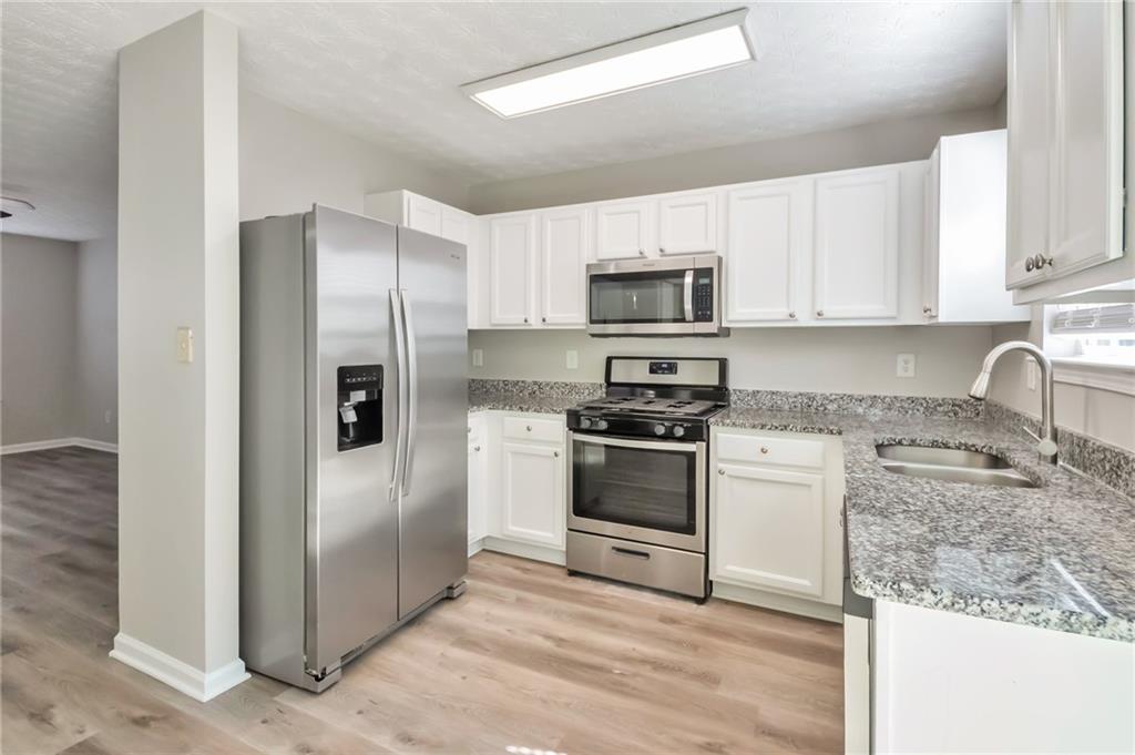 344 Springbottom Court Southeast Lawrenceville, GA 30046 - Photo 7 of 26 a kitchen with granite countertop a refrigerator stove and microwave