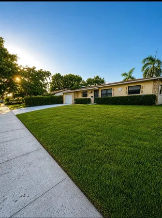 a view of a big yard with plants and large trees