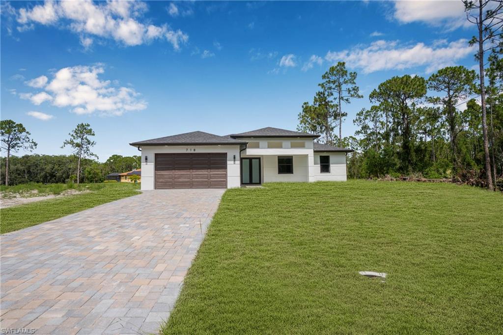 718 Bennington Drive Lehigh Acres, FL 33974 - Photo 2 of 5 a front view of a house with garden